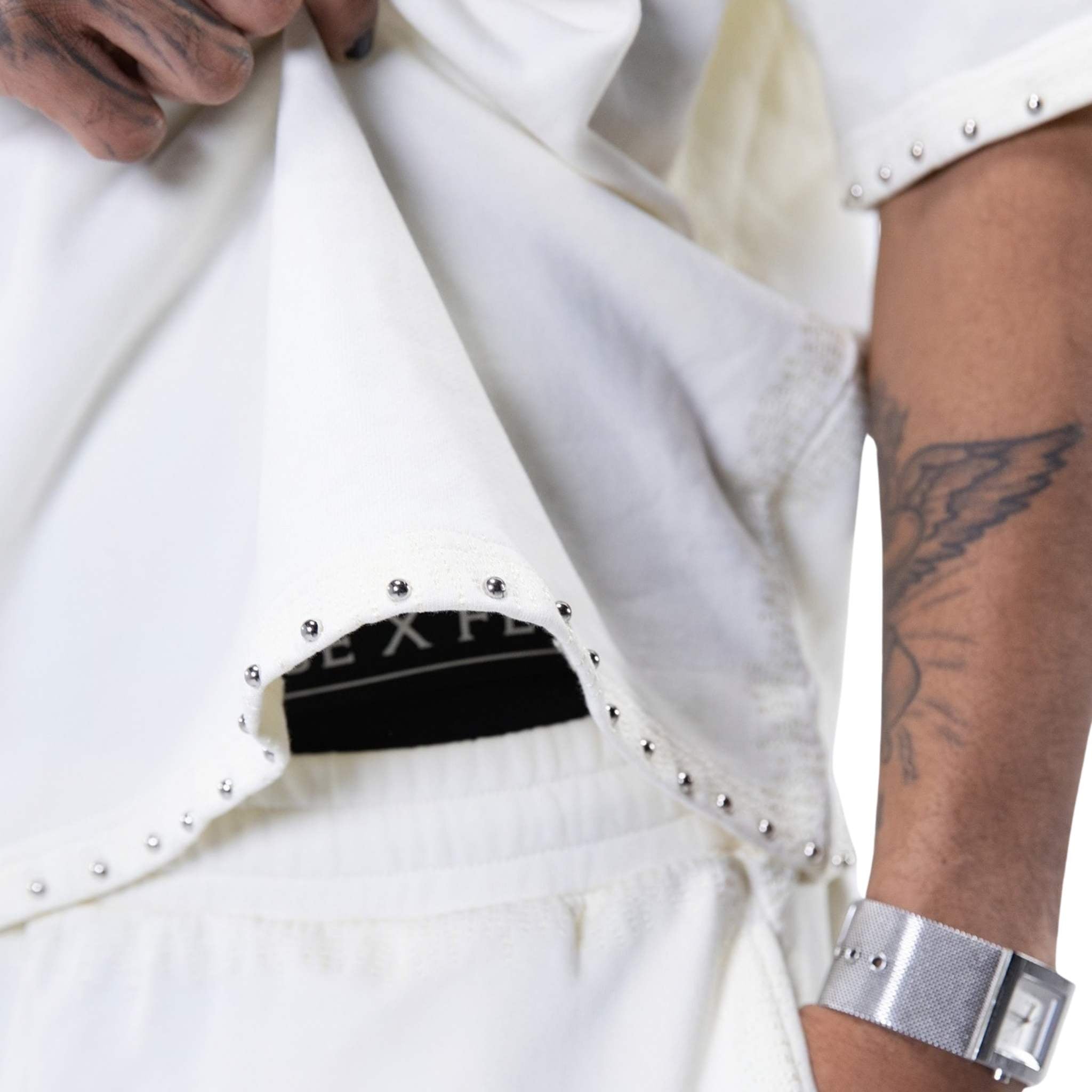 Close-up of studded hem detailing on white shirt